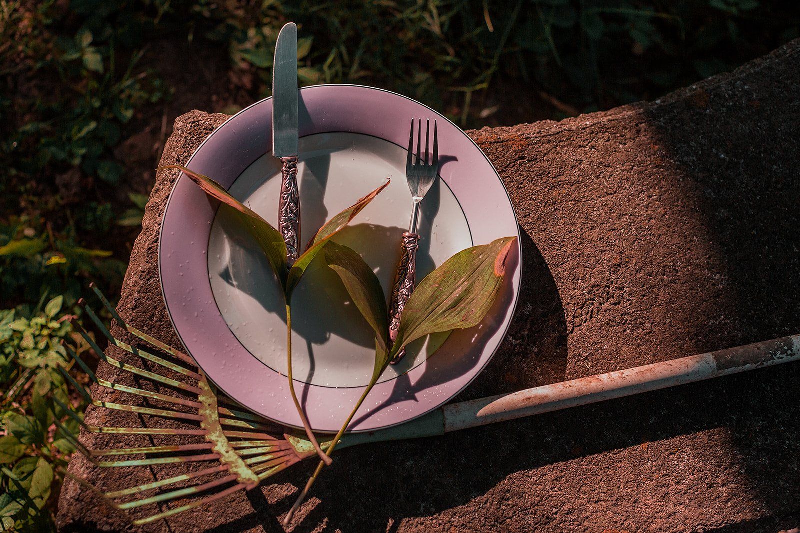 Pink plate and flatware on a woven mat