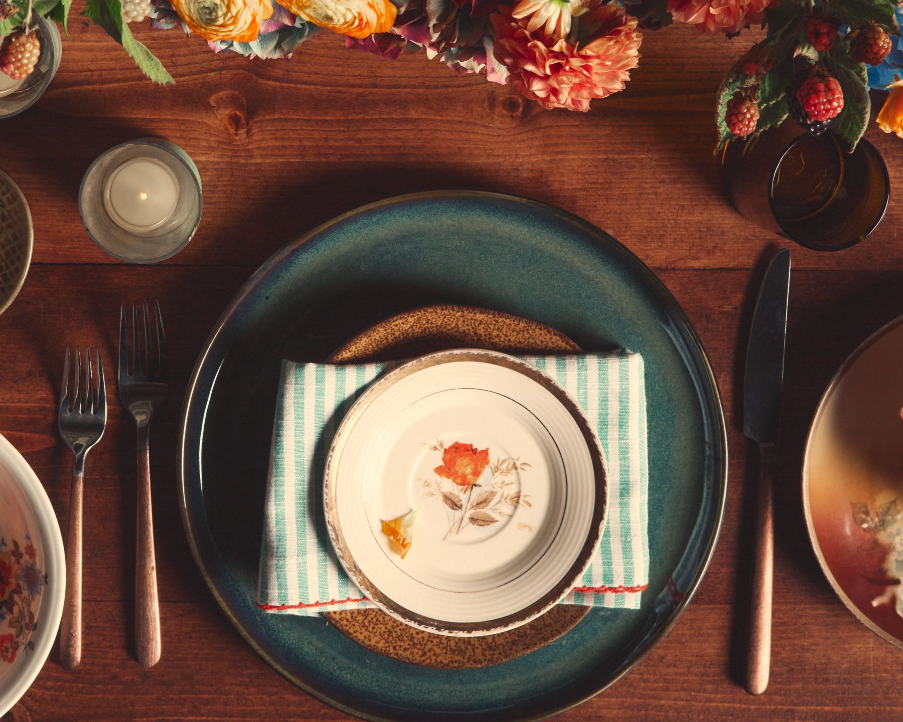 Layered green charger and floral china on a wooden table
